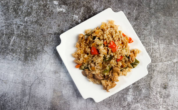 istock Chicken Bell Pepper Rice on a white square  plate on a dark background. Top view, flat lay 1423517945