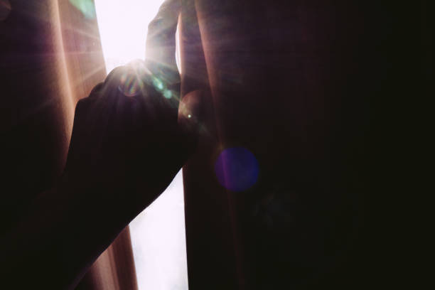 An image of a hand opening the curtain and the sunlight