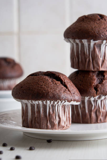 istock Delicious chocolate muffins in paper cups on a plate on white background. 1423521753
