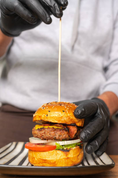 istock Cook sticking a skewer into a ready-to-eat hamburger 1423522398