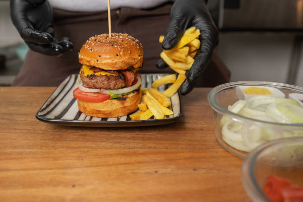 istock Chef adding fries to a hamburger in the kitchen of a restaurant 1423522400