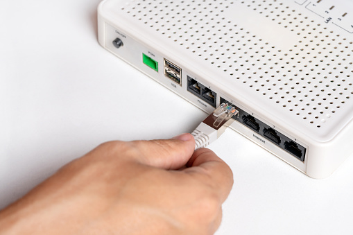 Hand connects network cable in socket of router. Concept of access to internet