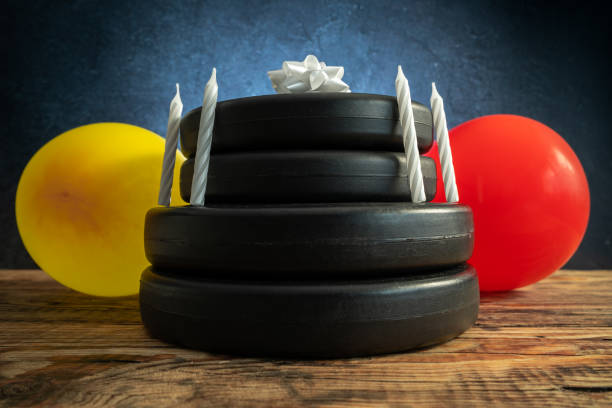 Heavy dumbbell barbell weight plates stacked on top of each other in the shape of a birthday cake, with candles and balloons. Gym exercise equipment as a gift idea. Healthy fitness lifestyle concept.