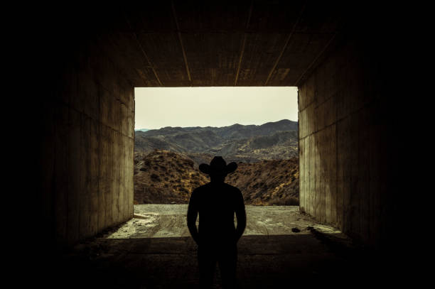 siluetta di uomo adulto in cappello da cowboy in piedi all'ingresso di un tunnel - the western wall foto e immagini stock