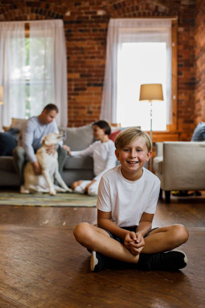 istock Cheerful boy sitting on the floor and joyfully smiling at camera 1423527830