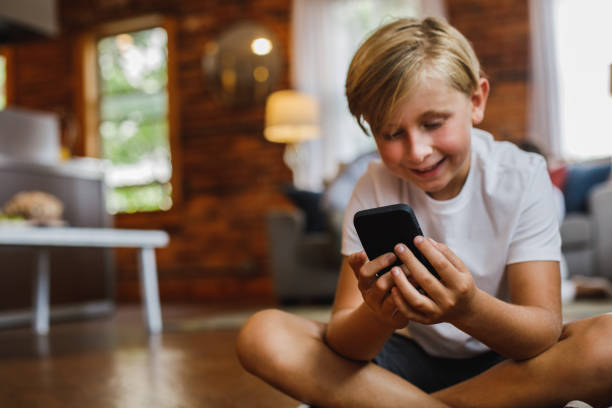 istock Cheerful boy smiling while watching a fun video on smart phone 1423527834