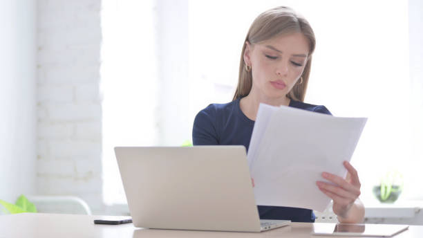 istock Woman with Laptop Reading Documents in Office 1423529693