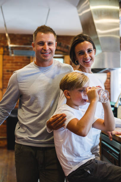 istock Couple standing embraced, smiling at camera while their son is drinking water 1423530203