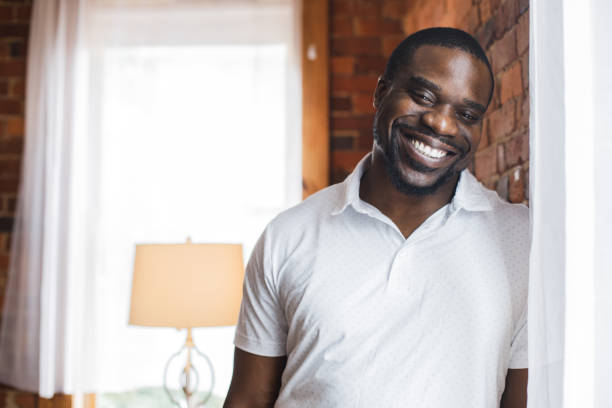 istock Cheerful Black man standing by the brick wall and joyfully smiling at camera 1423531968