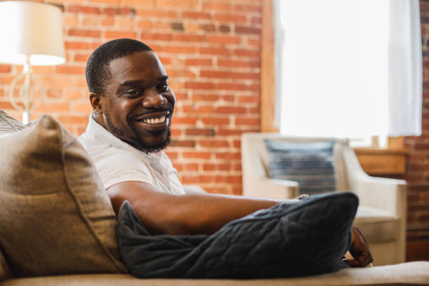 istock Charming Black man relaxing on the sofa and confidently smiling at camera 1423531990
