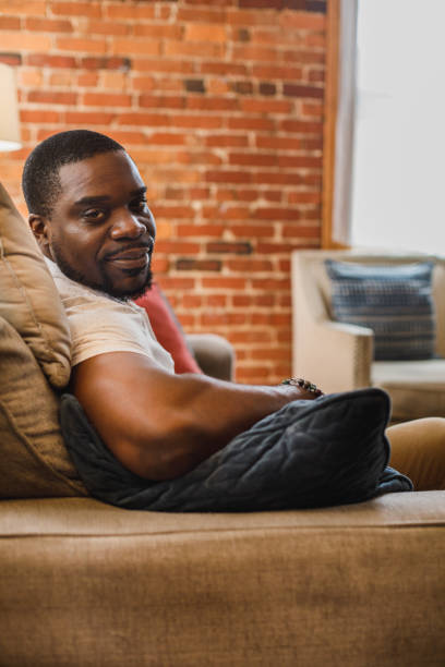 istock Charming Black man lounging on the sofa and smiling at camera 1423531999