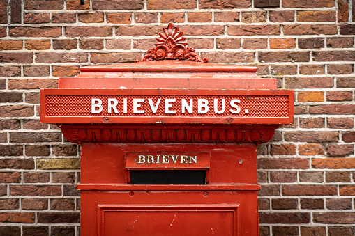 traditional old Dutch red postbox mounted in a cotswold stone wall