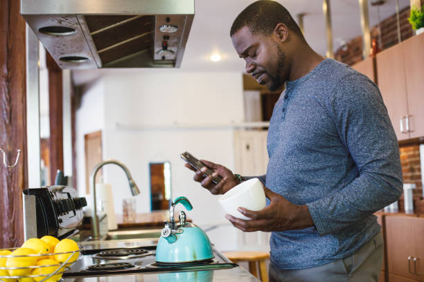 istock Frustrated man responding to a text message that interrupted him in preparing a cup of tea 1423533188