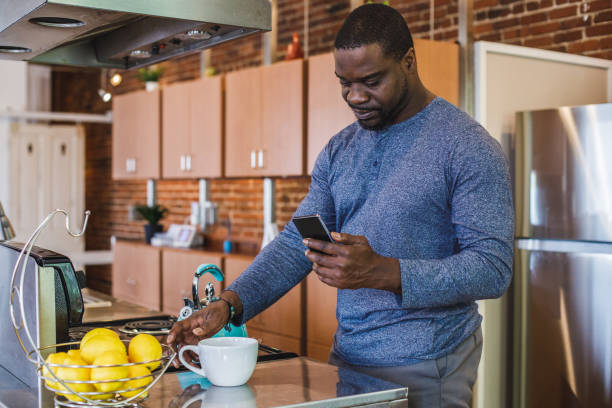 Man reaching for a cup of tea while scrolling through his smart phone