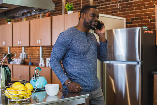 istock Man standing in the kitchen, pondering while talking on the phone with a friend 1423533199