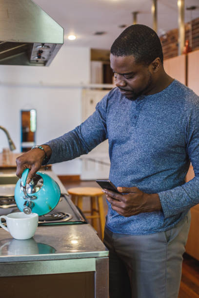 istock Man pouring hot boiling water from a tea kettle while making tea 1423533203