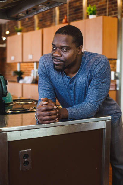 istock Man leaning against the kitchen counter, smiling and contemplating 1423533296