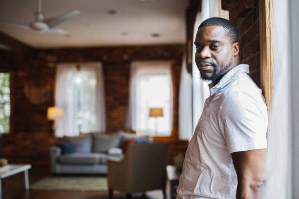 istock Side view of smug Black man standing against the wall, looking at camera, slightly smiling 1423533428