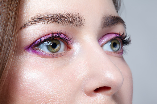 Closeup shot of human female face. Woman with natural face and eyes beauty pink makeup.