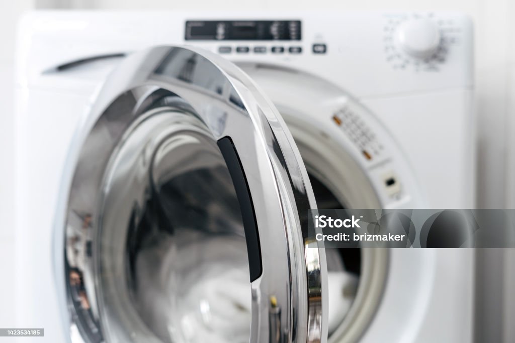 new washing machine with open door, closeup open door in automatic washing machine and clean clothes inside after laundry in apartment bathroom, modern domestic appliance Washing Machine Stock Photo