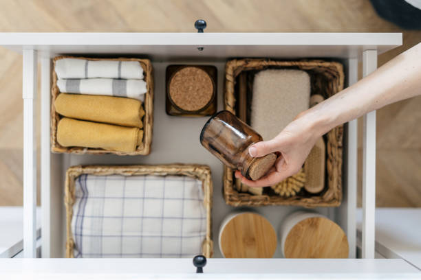 mulher pega frasco de vidro reciclado de gaveta aberta na cozinha - wicker drawers - fotografias e filmes do acervo