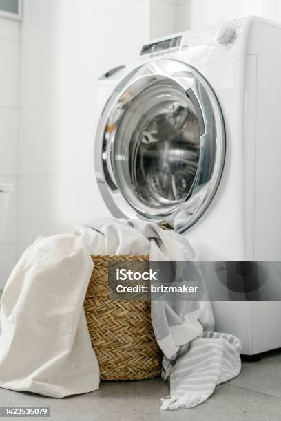 Dirty Bedding In Wicker Basket Near Washing Machine Indoors Stock Photo - Download Image Now