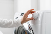 female hand choose mode with knob on washing machine indoors