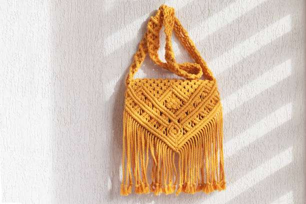 Handmade macrame cotton ross-body bag.  Eco bag for women from cotton rope. Scandinavian style bag.  Yellow color, sustainable fashion accessories. Details. Close up image stock photo