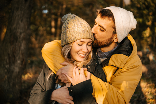 Portrait Of Happy Loving Couple With Man Giving Woman Piggyback As They Hug In Autumn Park Together