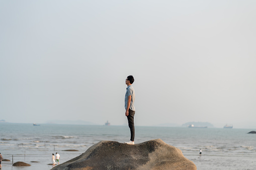 man standing on rock admiring sea view