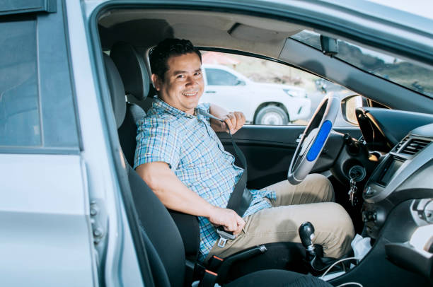 Smiling male driver putting on his seat belt. Concept of a driver in his car putting on his seat belt. Smiling person putting on seat belt, Happy driver putting on his seat belt conductor sonriente poniéndose el cinturón de seguridad. concepto de un conductor en su coche poniéndose el cinturón de seguridad. persona sonriente poniéndose el cinturón de seguridad, conductor feliz poniéndose el cinturón de seguridad