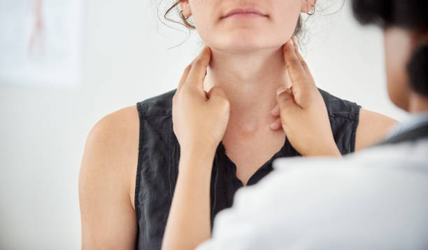 doctor checking thyroid of a young patient in clinic - menselijke nek stockfoto's en -beelden