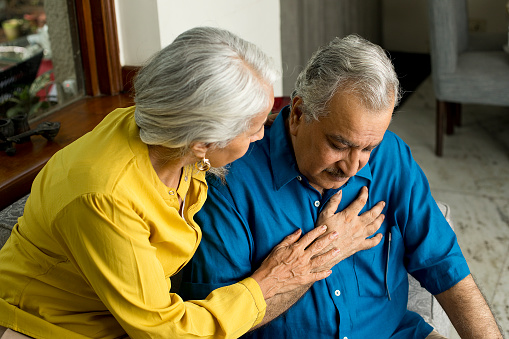 Wife comforting her husband suffering with severe chest pain