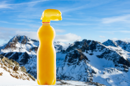 Plastic bottle for fruit juice drink with cold a fresh snowy landscape in the background. An everyday plastic bottle to serve fruits juices