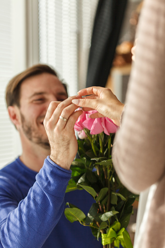 Close up shot of happy mid adult man putting engagement ring on his now finance's finger after she said yes.