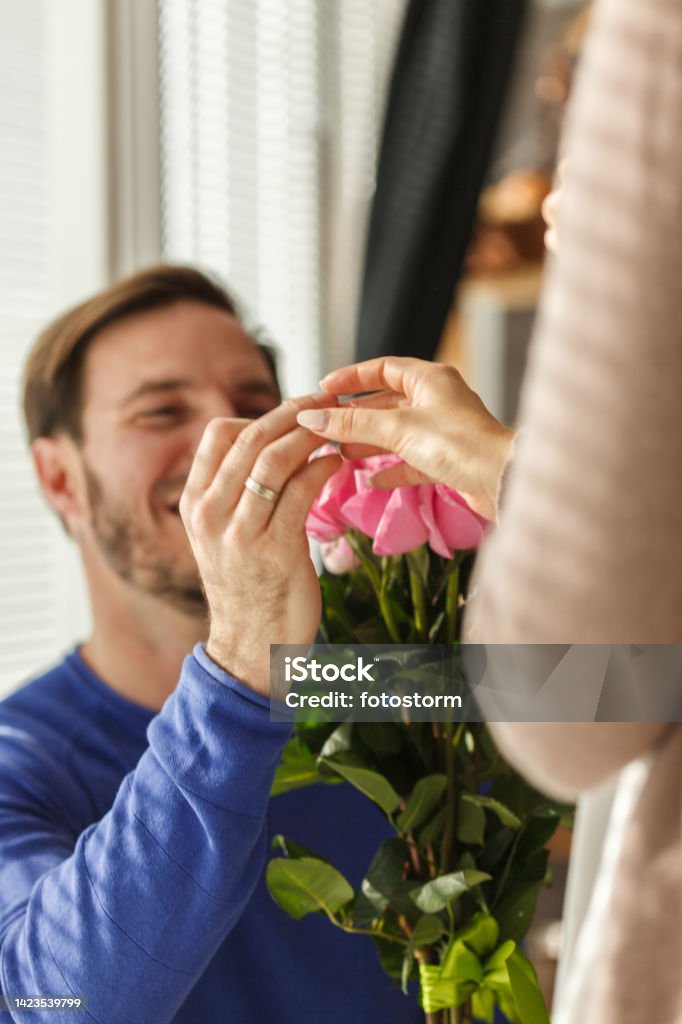 Man putting engagement ring on his now finance's finger after she said yes Close up shot of happy mid adult man putting engagement ring on his now finance's finger after she said yes. Couple - Relationship Stock Photo