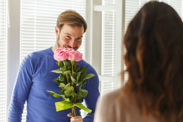 Man smelling the roses he is about to give to his loving wife stock photo