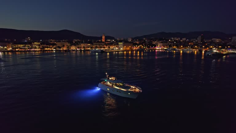 AERIAL Modern yacht in the bay of a coastal city at night