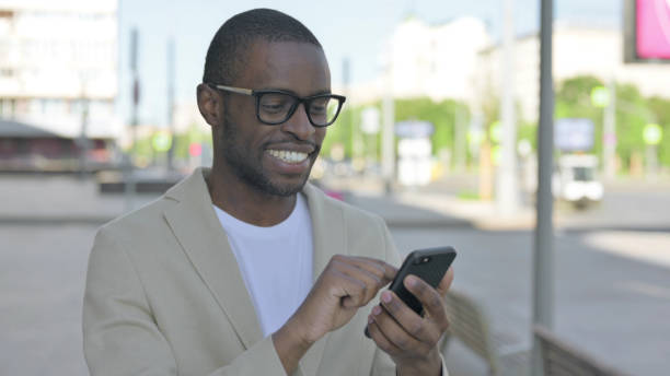 istock African Man Browsing Internet on Smartphone Outdoor 1423544872