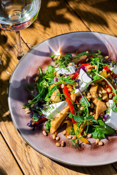 istock Wheat with fried chicken, pea sprouts, pepper, cheese, basil and mung bean salad in a plate on a wooden table with a glass of wine 1423545362