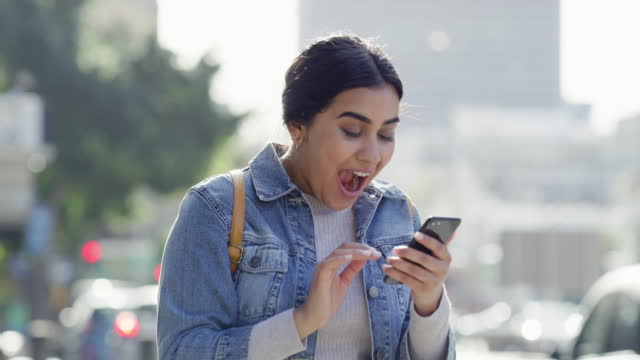 Wow, success and a winning woman text message on phone in an urban city, celebration and victory dance. Young, excited female reading of a sale or discount, cheerful after surprise promo code alert
