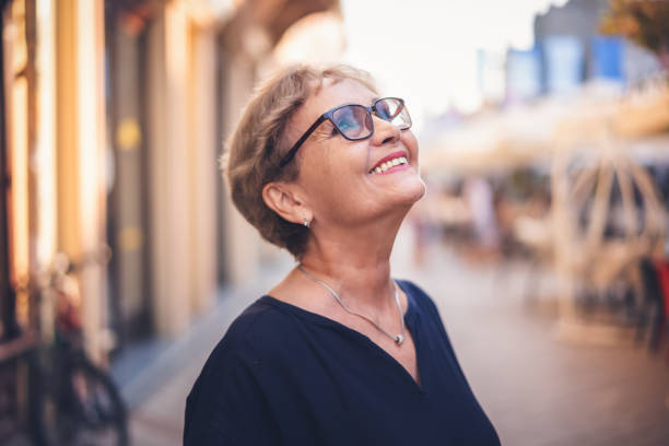 Portrait  of happy active senior woman in glasses with a beautiful smile in profile  walking in city on the street stock photo
