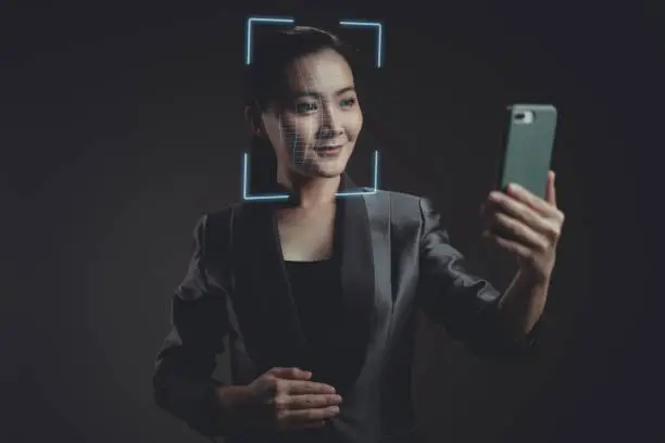 Photo of Asian woman scans face by smart phone using facial recognition system.