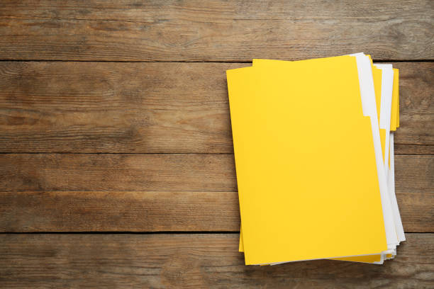 istock Yellow files with documents on wooden table, top view. Space for text 1423550533