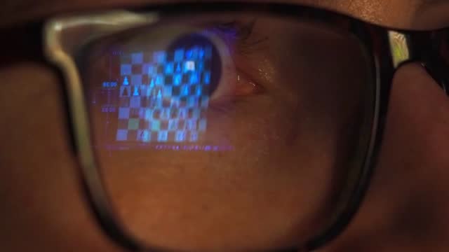 Eye of a woman with glasses looking attentively at the computer screen while playing chess on the internet