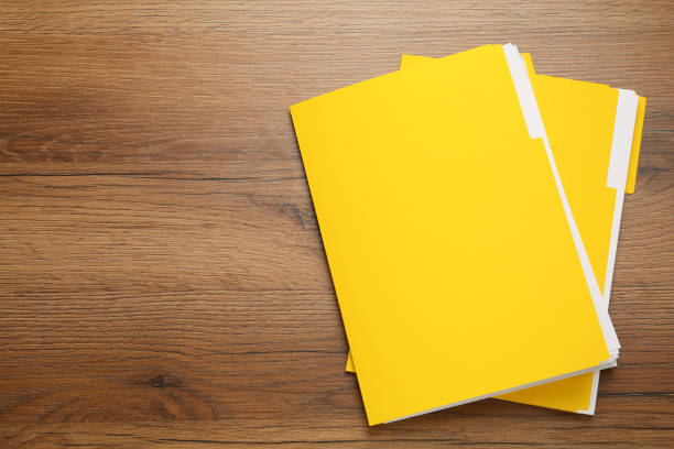 istock Yellow files with documents on wooden table, top view. Space for text 1423550613