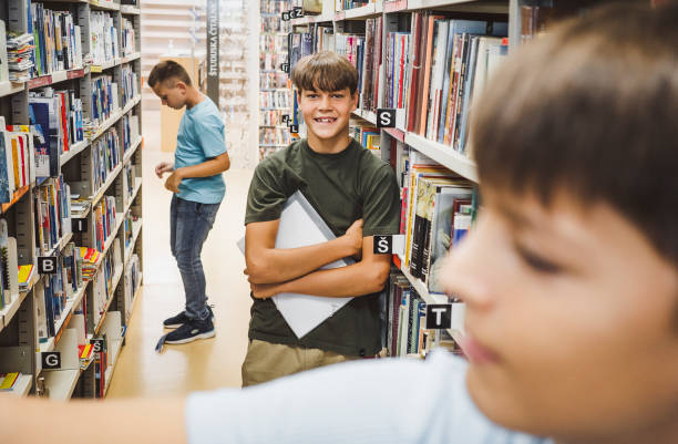 Young kids searching for books in the library stock photo
