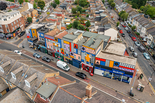 Aerial photo from a drone of Leyton High Street, High Road, Leyton, East London, Waltham Forest, London, UK. Including Walala Parade artwork on building.