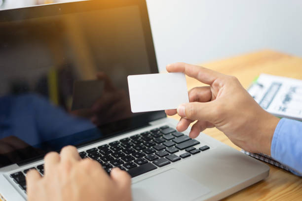 istock Bank, banking, bill.Online payment,Man's hands holding laptop and smartphone ,using credit card for online shopping.typing numbers on computer keyboard at home at the wooden table ,vintage color. 1423555607