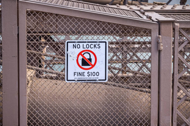 Brooklyn Bridge, Manhattan, New York, NY, USA - July 14th 2022: Sign telling it is illegal to place padlocks - as a symbol of eternal love - on the bride and that the fine is $100 in you are caught